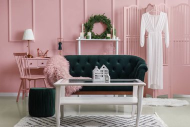 İçinde yeşil kanepe, masa ve Noel dekoru olan oturma odası.