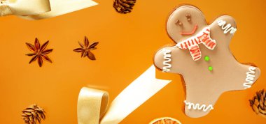 Turuncu arka planda Noel süslemeleri olan zencefilli kurabiye.