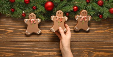Kadın eli, Noel kurabiyesi ve tahta arka planda köknar dalları.