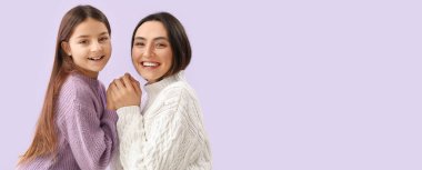 Küçük kız ve annesi sıcak süveter giyip el ele tutuşuyorlar.