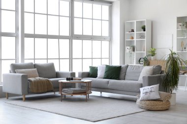 Işıl ışıl oturma odası, rahat gri koltuklar ve kahve masası.