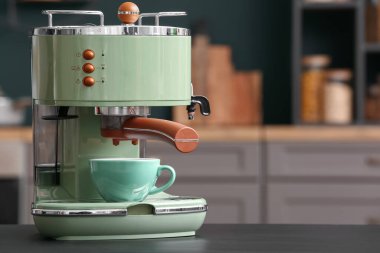 Mutfaktaki siyah masada fincanlı modern kahve makinesi, yakın plan.