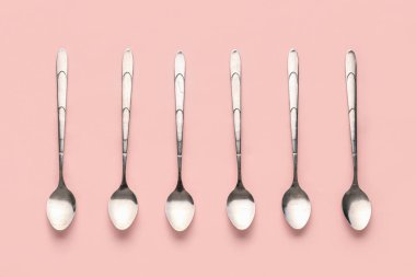 Pembe arka planda paslanmaz çelik kaşıklar