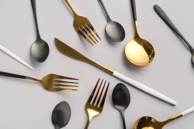 Gri arkaplanda farklı paslanmaz çelik çatal bıçak seti