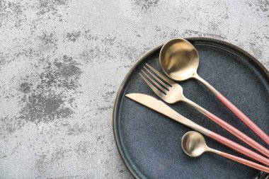 Pembe saplı gümüş çatal bıçak seti ve gri arka planda tepsi.