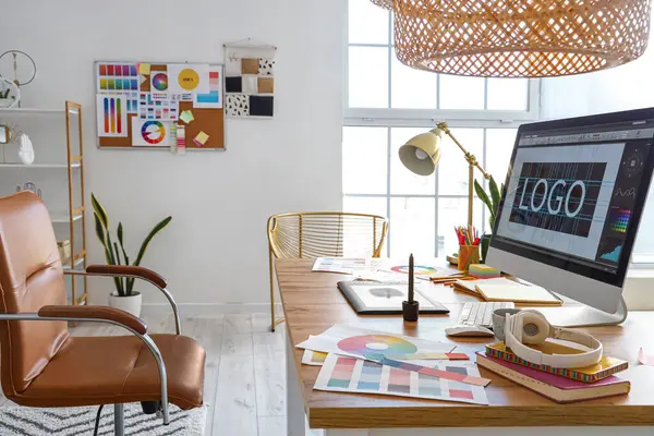 Graphic designer\'s workplace with computer, tablet and paint palettes in office