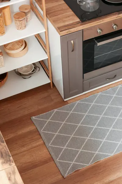 Stylish grey rug on floor in kitchen