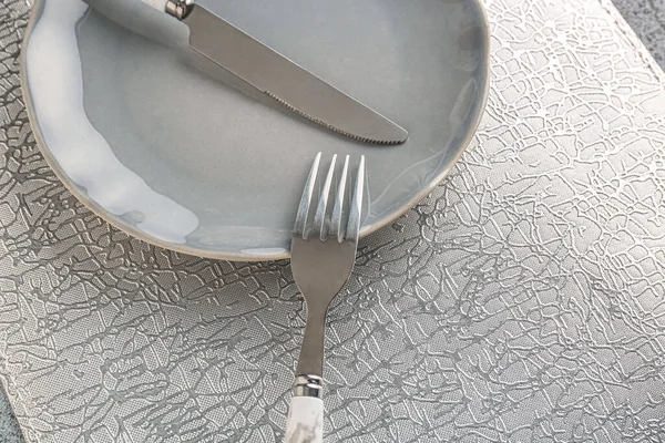 Silver fork with knife, plate and kitchen mat on grey grunge table