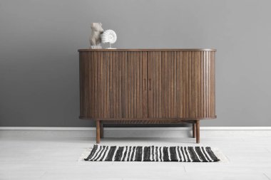 Gri duvarın yanındaki çekmeceli ahşap sandık.