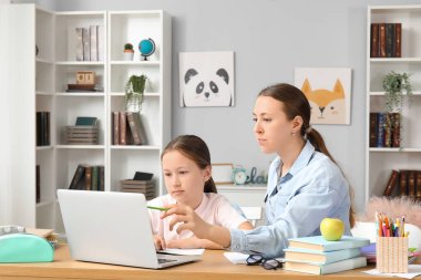 Evde annesiyle ders alan sevimli küçük bir kız.