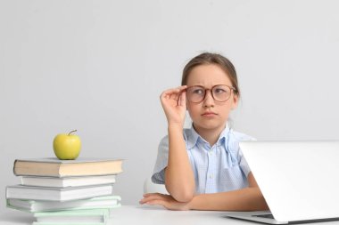 Işık duvarının yanındaki masada ödev yapan sevimli küçük kız.