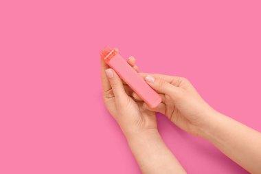 Pembe arka planda elektronik sigara tutan kadın.
