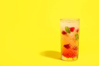 Sarı arka planda bir bardak taze ahududu mojito.
