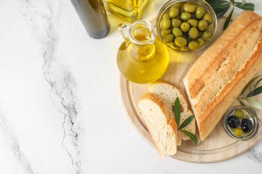 Beyaz mermer arka planda tahtadan ekmek, zeytin ve yağ.