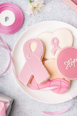 Üzerinde gri grunge arka planda kurdele şeklinde pembe kurabiyeler olan bir tabak. Göğüs kanseri farkındalığı konsepti