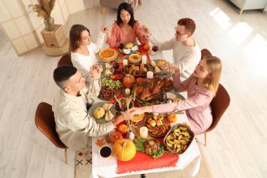 Şükran Günü 'nde şenlik masasında dua eden bir grup genç arkadaş.