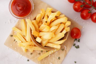 Beyaz arka planda ketçaplı bir kase lezzetli patates kızartması.