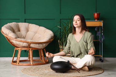 Glukofonlu genç bir kadın evde meditasyon yapıyor.