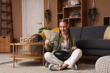 Elinde sopalarla evde glukofon çalan genç bir kadın.