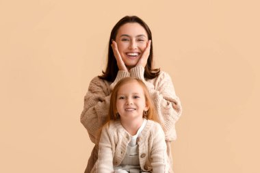 Mutlu genç anne ve küçük kızı bej arka planda