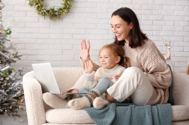 Mutlu bir genç anne ve dizüstü bilgisayarlı küçük kızı Noel arifesinde evde sohbet ediyorlar.