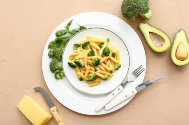 Brokolili lezzetli makarna ve bej arka planda avokado.