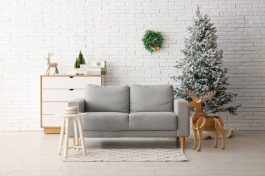 Güzel bir Noel ağacı, çekmeceleri ve beyaz tuğla duvarın yanındaki rahat kanepesi.