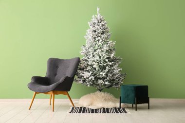Rahat koltuğu ve yeşil duvarı olan güzel bir Noel ağacı.
