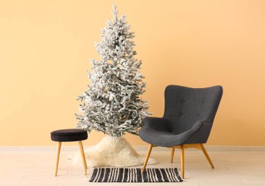 Bej duvarın yanında rahat koltuğu olan güzel Noel ağacı