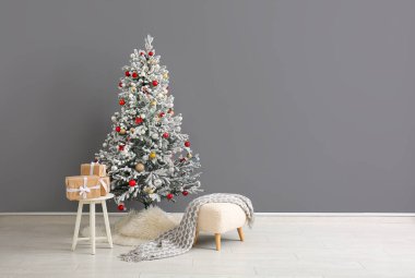 Güzel bir Noel ağacı hediye kutuları ve gri duvarın yanında bir kanepe