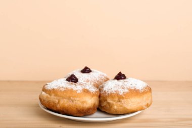 Hanuka kutlaması için lezzetli çöreklerle dolu tabaklar ahşap masada renk arka planına karşı.
