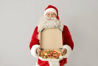 Beyaz arka planda bir kutu lezzetli pizza olan Noel Baba.