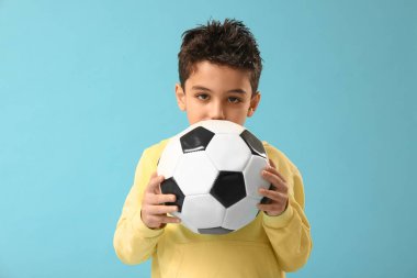 Mavi arka planda futbol topu olan şirin bir çocuk.