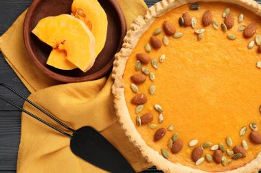 Bademli balkabaklı tart ve siyah ahşap arka planda tohumlar.