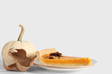 Beyaz arka planda lezzetli balkabaklı tart ve sonbahar yapraklı tabak.