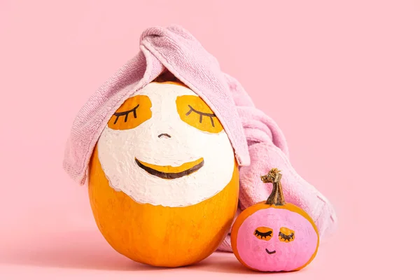 Pumpkins with drawn faces and masks on pink background