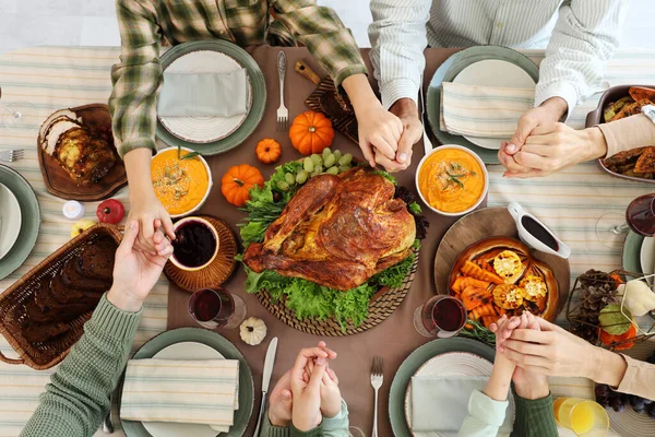 Happy family praying before dinner at festive table on Thanksgiving Day, top view