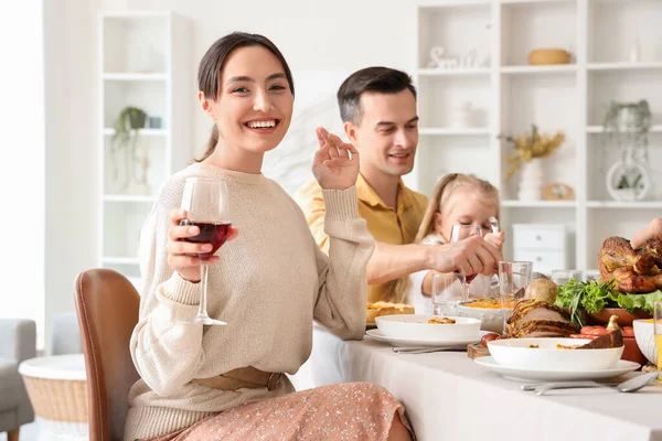 Young woman having family dinner at festive table on Thanksgiving Day