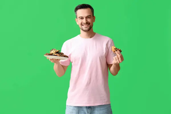 Schöner Mann Mit Einem Teller Leckerer Kekse Auf Grünem Hintergrund — Stockfoto