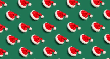 Yeşil arka planda bir sürü Noel Baba şapkası. Tasarım için desen