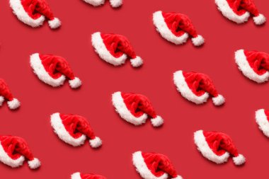 Kırmızı arka planda bir sürü Noel Baba şapkası var. Tasarım için desen