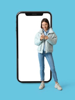 Kalın elbiseli güzel bir bayan ve açık mavi arka planda büyük bir akıllı telefon.