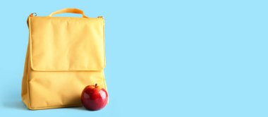 Açık mavi arkaplan üzerinde öğle yemeği çantası ve elma metin için boşluk