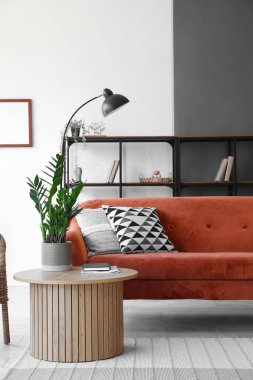 Modern oturma odasının içinde rahat bir kanepe ve sehpanın üzerinde çiçek var.