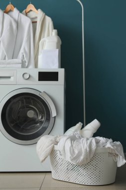 Bornozlarla, çamaşır sepetiyle ve mavi duvarın yanındaki çamaşır makinesiyle doldur.