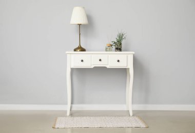 Beyaz duvarın yanında lamba olan giyinme masası.