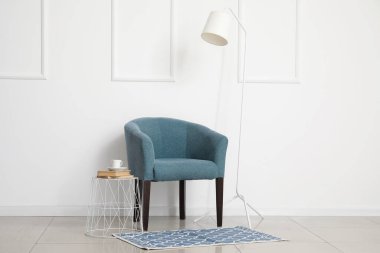 Beyaz duvarın yanında rahat koltuk ve standart lamba.