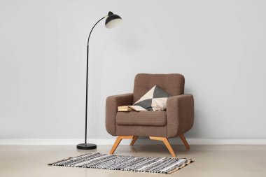 Yastıklı rahat koltuk ve beyaz duvarın yanında standart lamba.