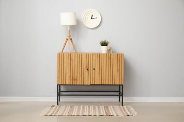 Masa lambalı ahşap dolap ve beyaz duvarın yanında bitkiler.