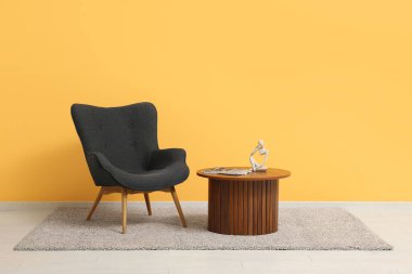 Dergileri, dekorasyonu ve renkli duvarın yanındaki rahat koltuğu olan ahşap masa.